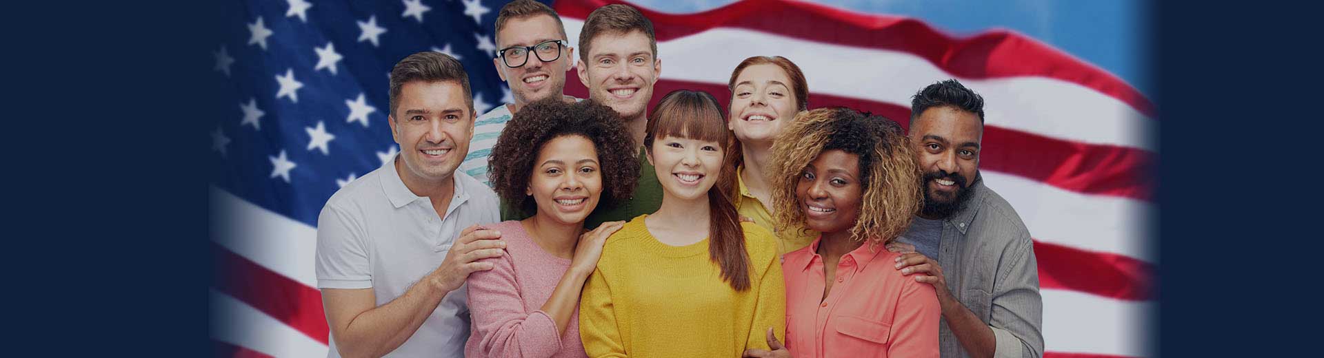 U.S. flag with a group of diverse men and women standing in front of it.